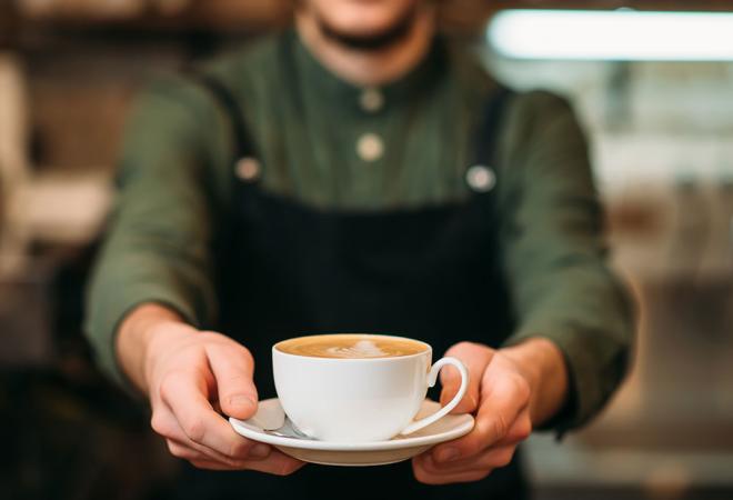 Un barista offre un cappuccino caldo, trasmettendo calore e accoglienza.