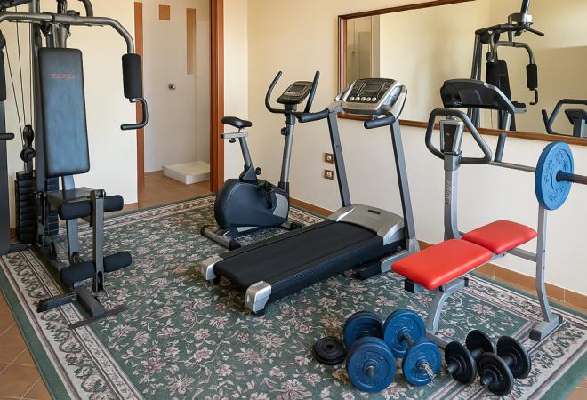 Palestra accogliente con attrezzi moderni, tappeto elegante e specchio grande.