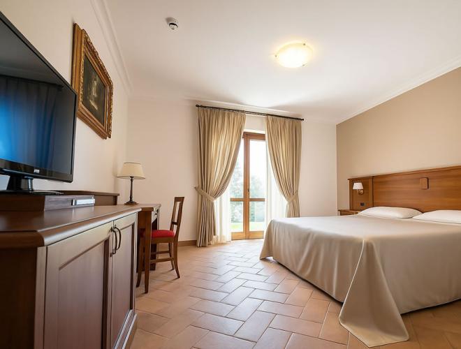 Camera accogliente e luminosa con letto matrimoniale e mobili in legno.