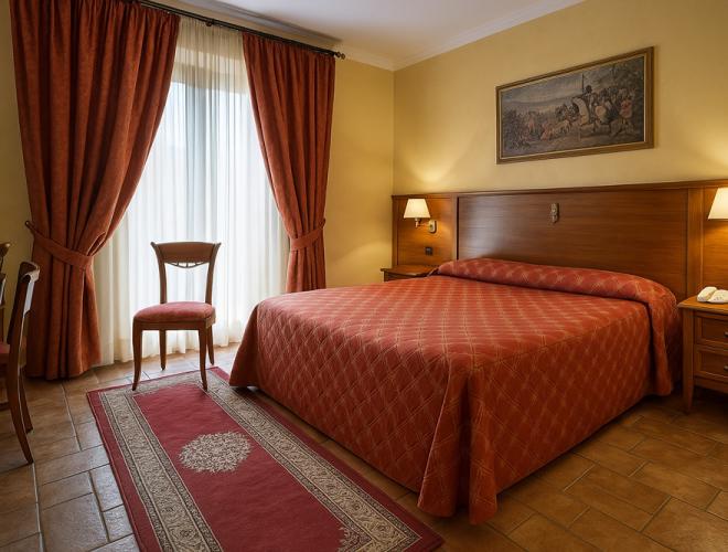 Camera accogliente con letto matrimoniale, tende rosse e atmosfera calda.