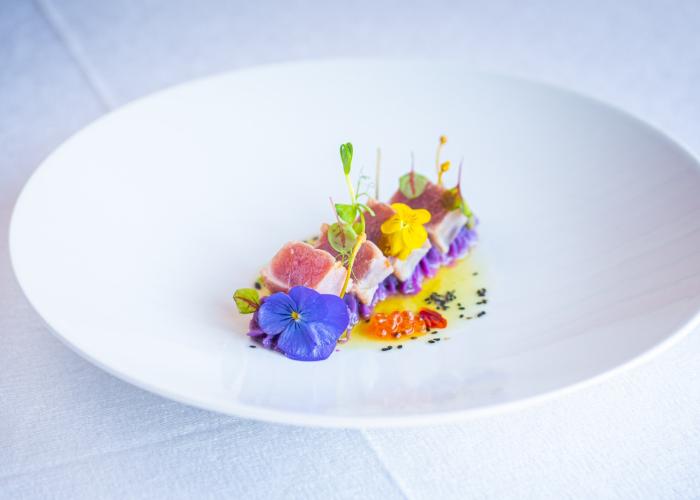 Piatto elegante con tonno, fiori colorati e decorazioni delicate.